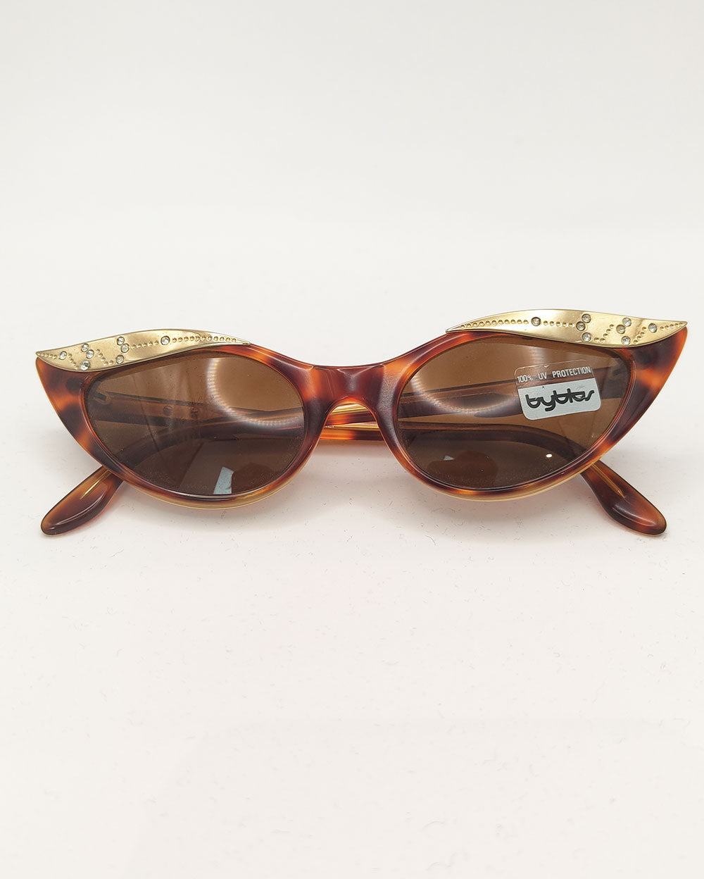An image of a pair of vintage Byblos sunglasses in a brown tortoiseshell with rhinestone beaded cat eye lens.