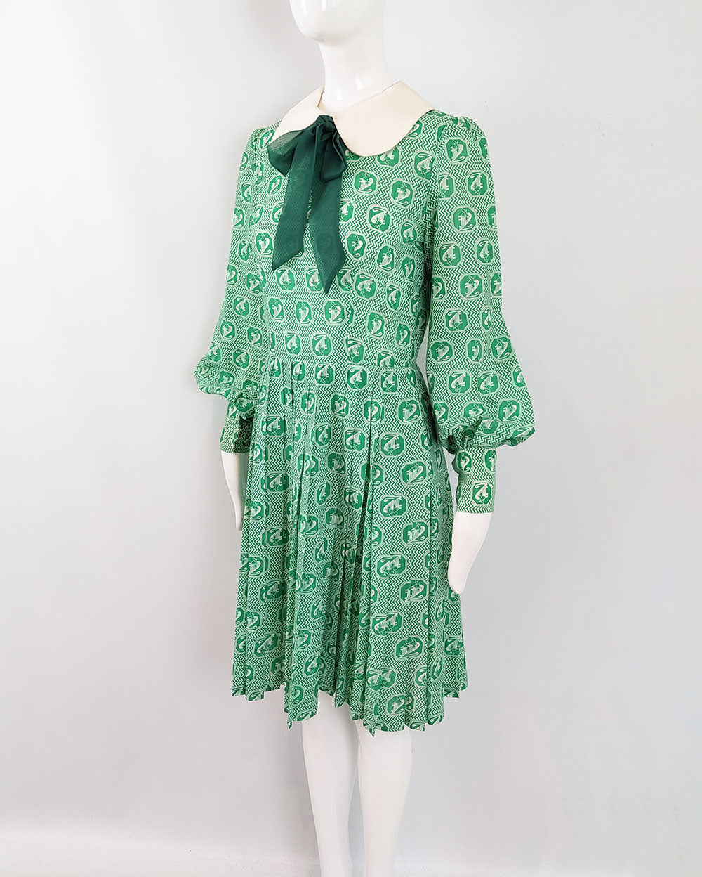 A vintage 1960s Jean Allen green pussybow dress with bishop sleeves and a pleated skirt.